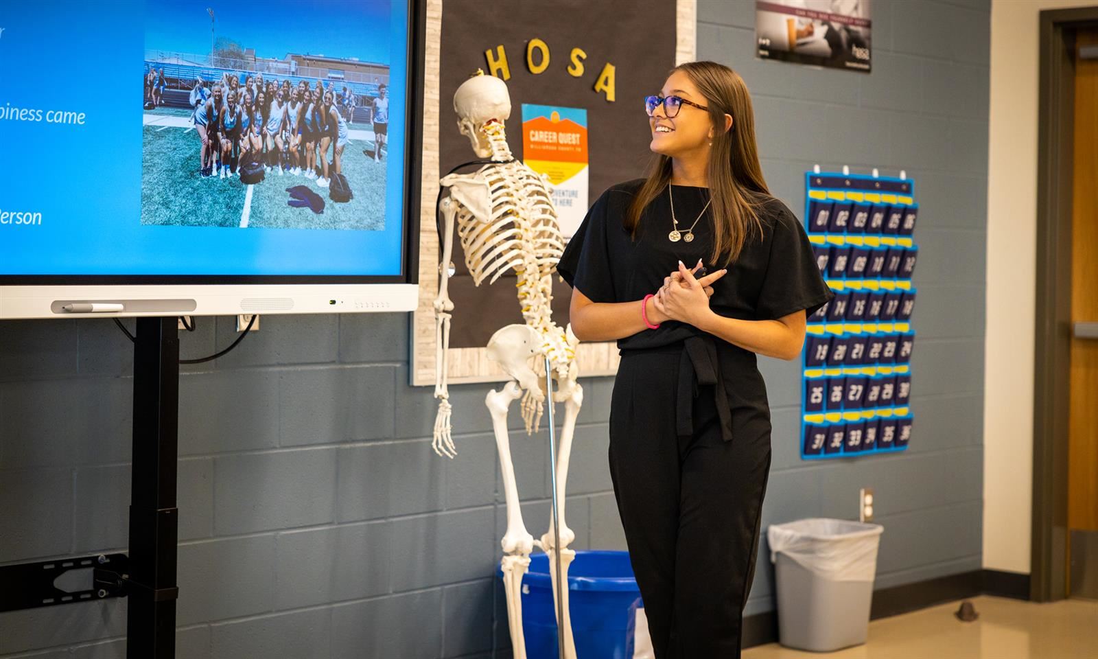 A girl gives a presentation at the front of a classroom